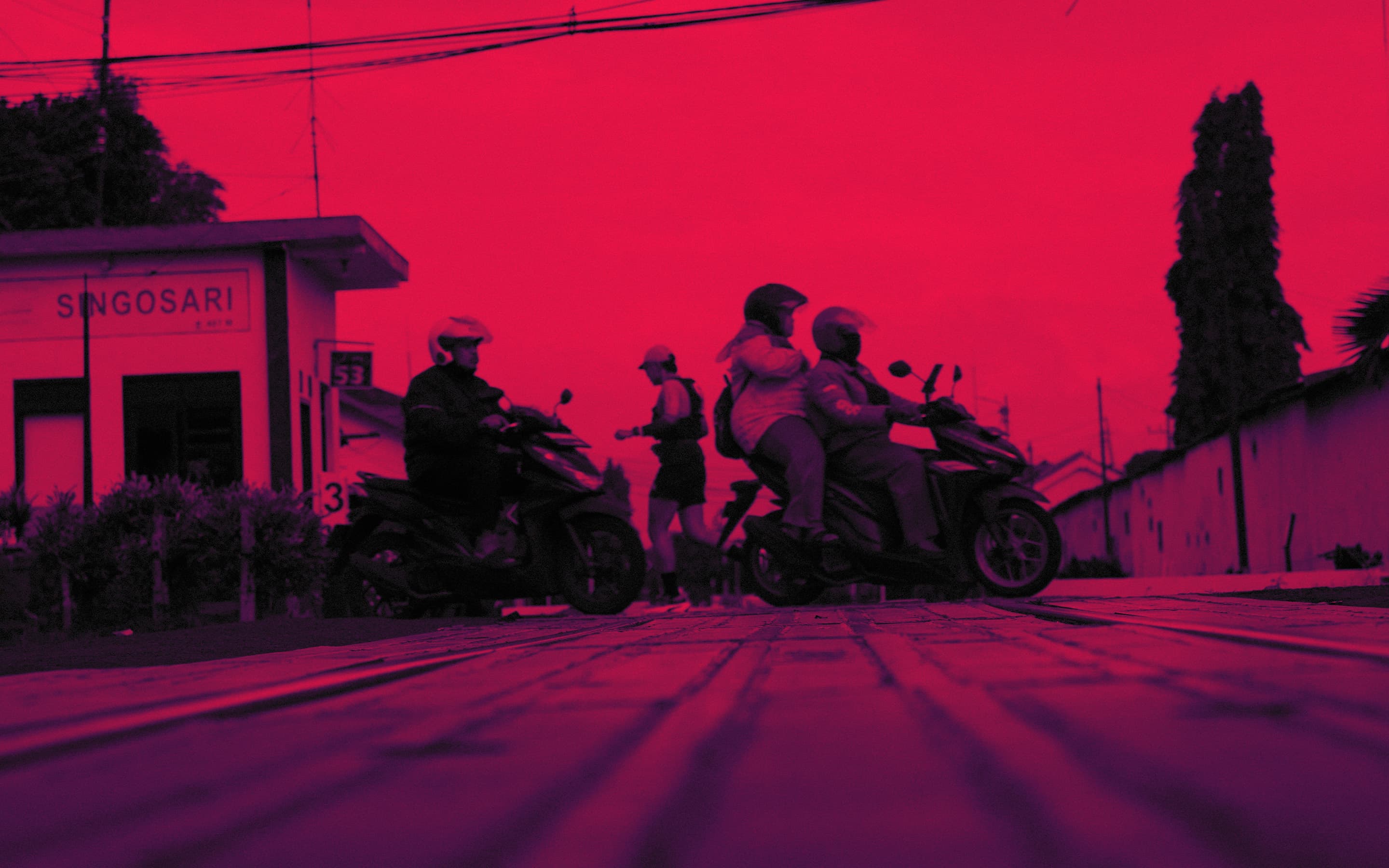 Runners and motorbikes on the road at Singosari, Jawa Timur, at dusk.